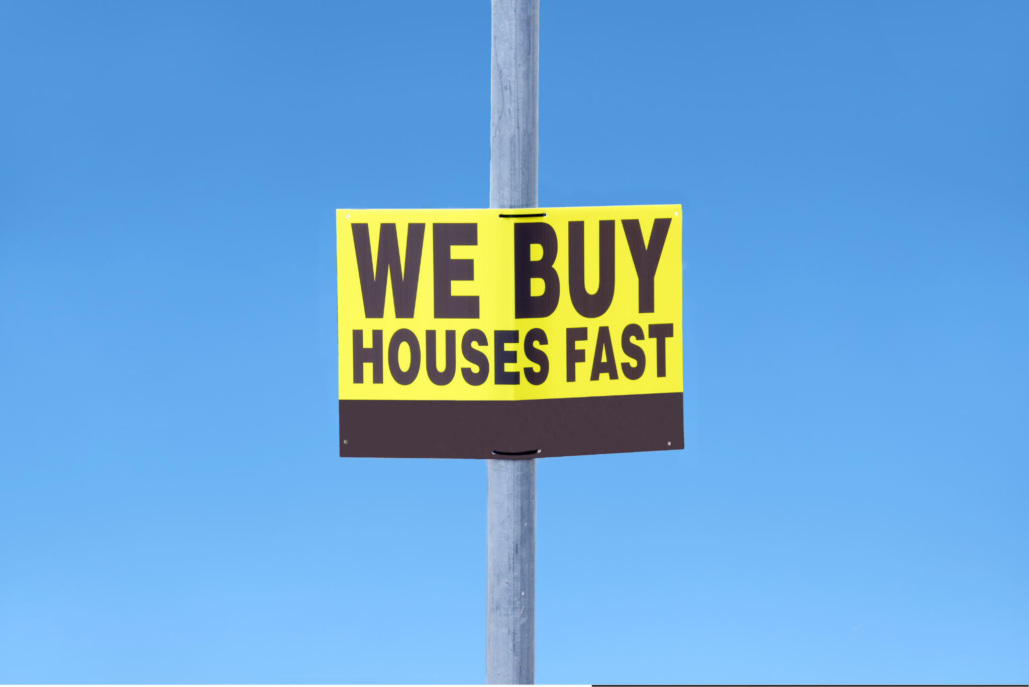 A bright yellow and black sign reads "We Buy Houses Fast" attached to a pole against a clear blue sky.